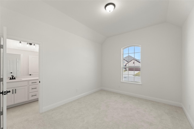 empty room with light carpet, vaulted ceiling, and sink