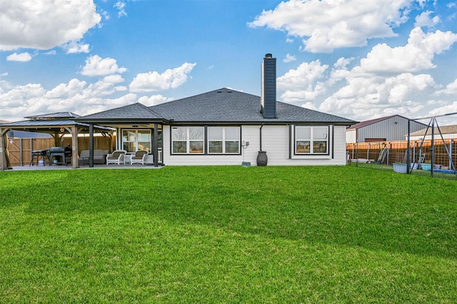 rear view of property with a gazebo, a patio, and a lawn