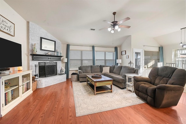 living room featuring ceiling fan, lofted ceiling, wood-type flooring, and a fireplace