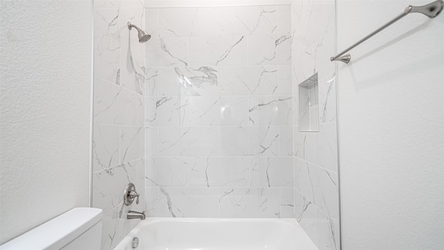 bathroom with tiled shower / bath combo and toilet