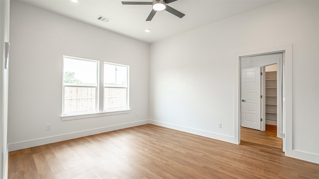 unfurnished bedroom with a closet, light hardwood / wood-style floors, a spacious closet, and ceiling fan