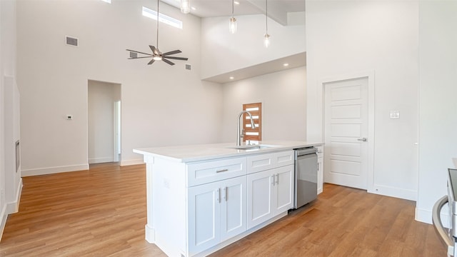 kitchen with dishwasher, white cabinets, sink, ceiling fan, and a towering ceiling