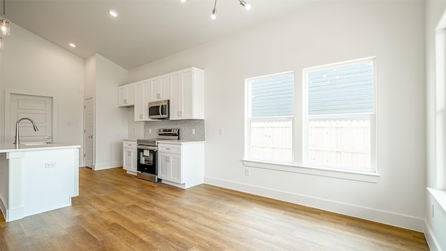 kitchen featuring sink, white cabinets, stainless steel appliances, and light hardwood / wood-style flooring