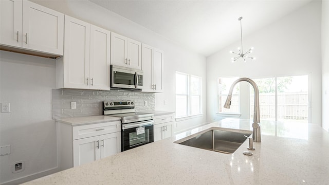 kitchen featuring light stone countertops, appliances with stainless steel finishes, sink, white cabinetry, and lofted ceiling