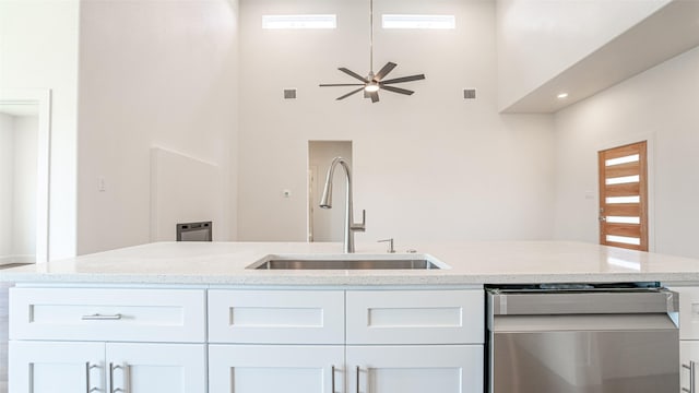 kitchen featuring dishwasher, sink, ceiling fan, a towering ceiling, and white cabinetry