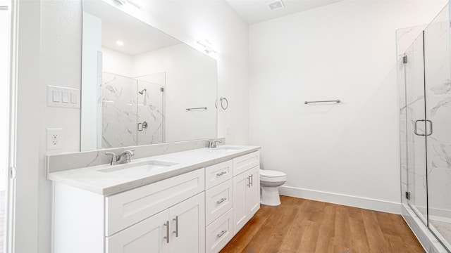 bathroom featuring wood-type flooring, vanity, toilet, and an enclosed shower