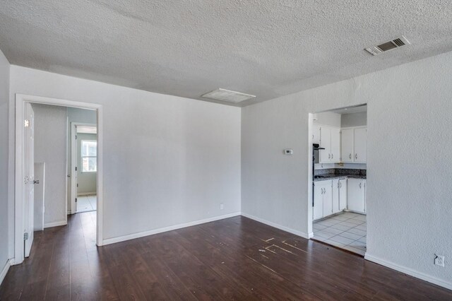 empty room with dark hardwood / wood-style floors and a textured ceiling