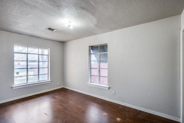 unfurnished room with a textured ceiling, dark hardwood / wood-style flooring, and a healthy amount of sunlight