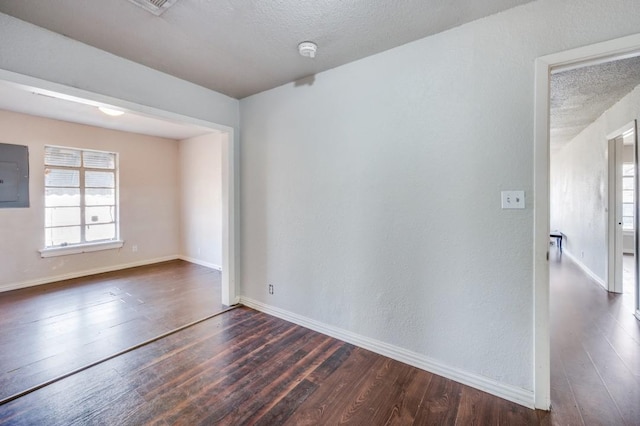 unfurnished room featuring electric panel, dark hardwood / wood-style flooring, and a textured ceiling