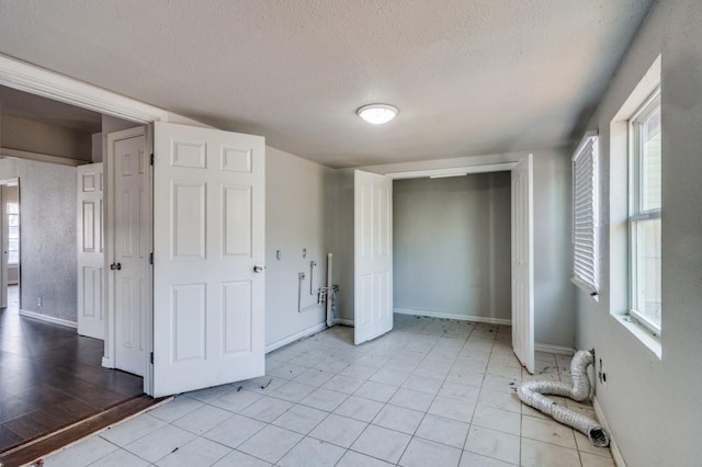 unfurnished bedroom featuring a closet, light tile patterned floors, and a textured ceiling