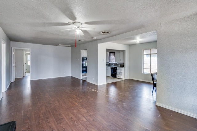 unfurnished living room with dark hardwood / wood-style floors, ceiling fan, and a textured ceiling