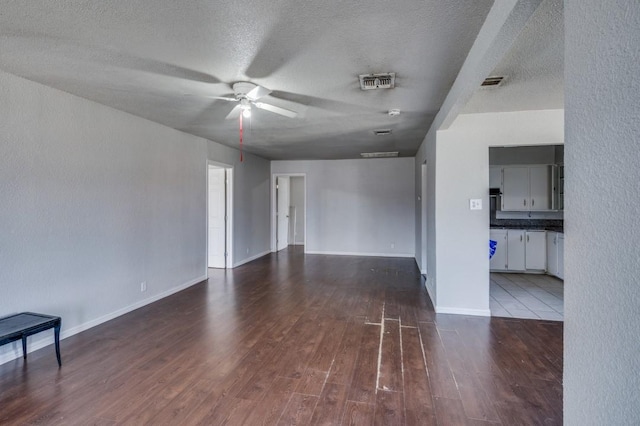 spare room with a textured ceiling, ceiling fan, and dark wood-type flooring