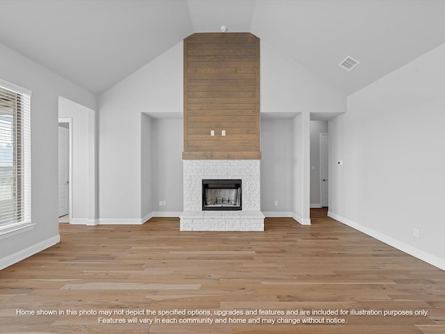 unfurnished living room featuring high vaulted ceiling, a fireplace, and light hardwood / wood-style floors