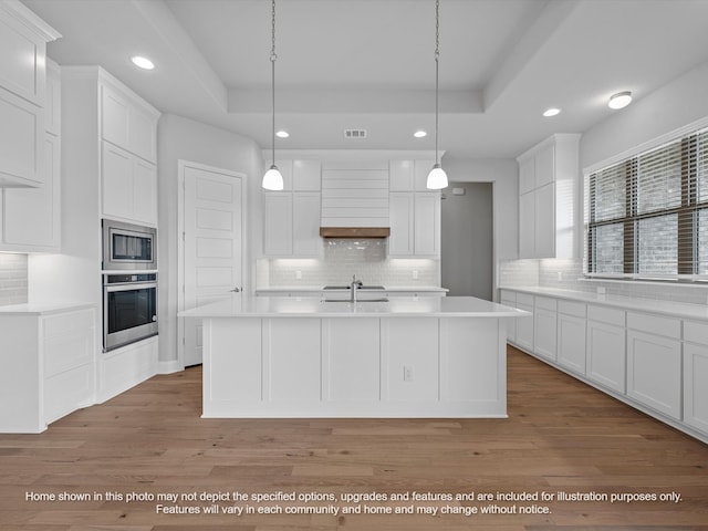 kitchen featuring stainless steel appliances, white cabinetry, pendant lighting, and a tray ceiling