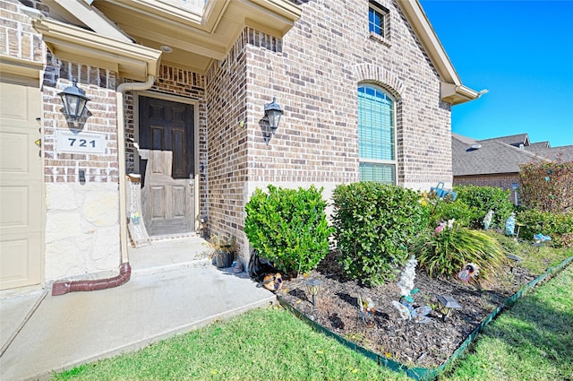 view of exterior entry with brick siding and a garage