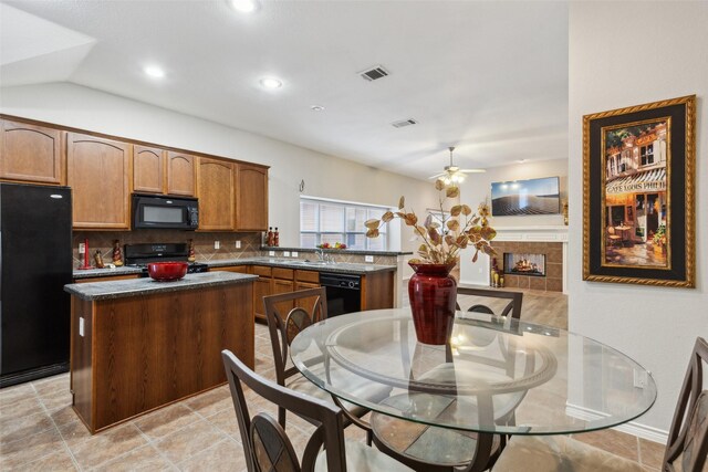 kitchen with ceiling fan, kitchen peninsula, vaulted ceiling, a fireplace, and black appliances