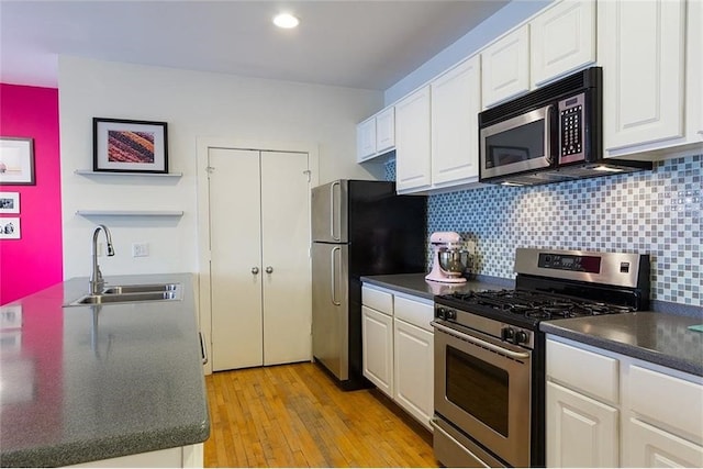 kitchen featuring decorative backsplash, stainless steel appliances, sink, light hardwood / wood-style flooring, and white cabinets