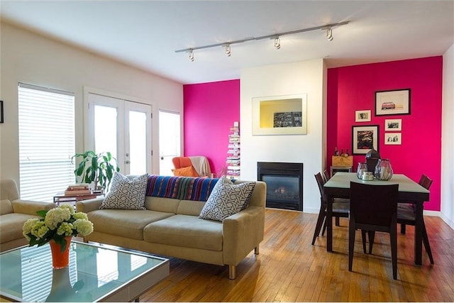 living room with french doors, track lighting, and hardwood / wood-style flooring