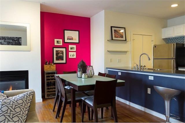 dining room with sink, beverage cooler, and hardwood / wood-style floors