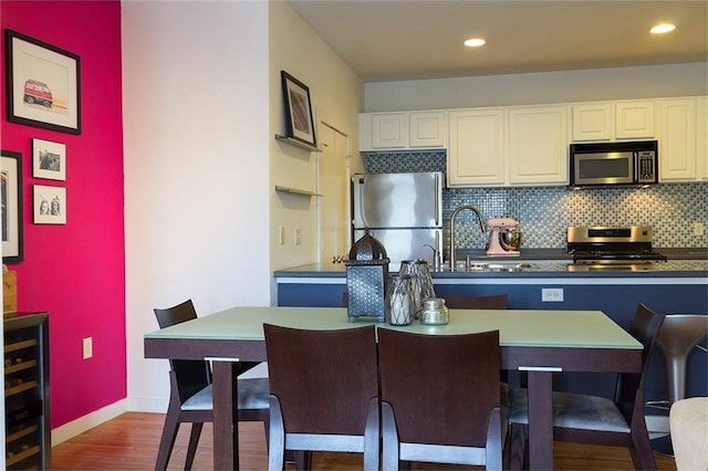 kitchen with sink, stainless steel appliances, dark hardwood / wood-style floors, decorative backsplash, and white cabinets