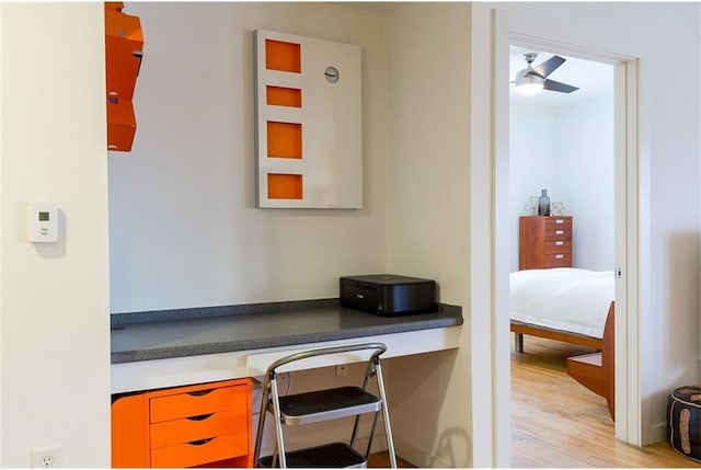 office with ceiling fan, built in desk, and light hardwood / wood-style floors