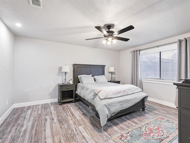 bedroom featuring ceiling fan, wood-type flooring, and a textured ceiling