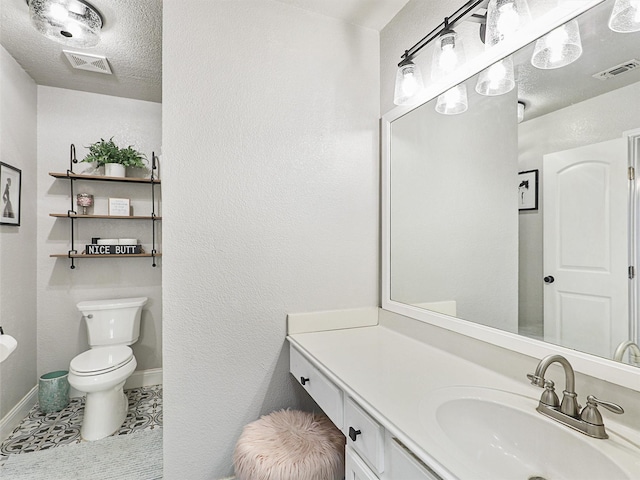 bathroom with tile patterned flooring, vanity, toilet, and a textured ceiling