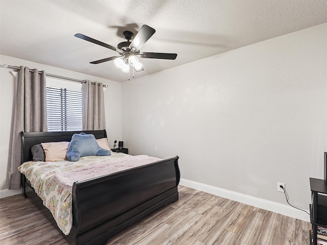 bedroom with ceiling fan, a textured ceiling, and hardwood / wood-style flooring