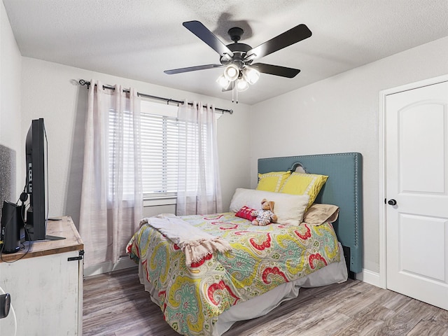 bedroom featuring ceiling fan, wood-type flooring, and a textured ceiling