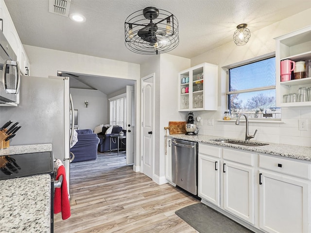 kitchen featuring white cabinetry, sink, light stone counters, light hardwood / wood-style floors, and appliances with stainless steel finishes