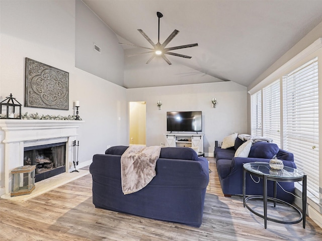 living room with ceiling fan, wood-type flooring, and vaulted ceiling