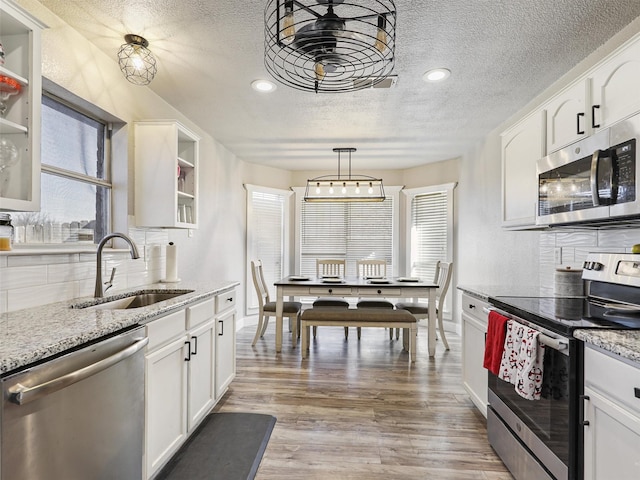 kitchen with sink, white cabinetry, stainless steel appliances, and hanging light fixtures