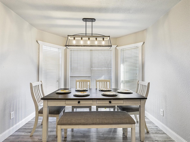 dining room with wood-type flooring and a textured ceiling