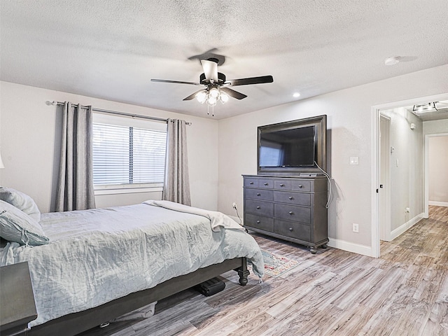 bedroom with ceiling fan, light hardwood / wood-style flooring, and a textured ceiling