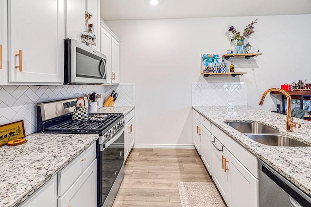 kitchen with tasteful backsplash, sink, white cabinets, and appliances with stainless steel finishes