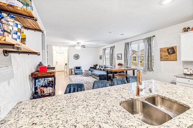 kitchen with white cabinets, light stone counters, sink, and tasteful backsplash