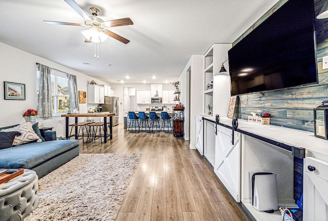 living room with ceiling fan and light hardwood / wood-style floors