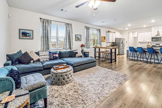 living room with light hardwood / wood-style floors and ceiling fan