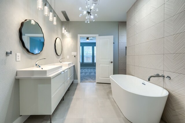 bathroom featuring vanity, tile patterned flooring, ceiling fan, a tub to relax in, and tile walls