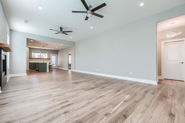 unfurnished living room with ceiling fan, light hardwood / wood-style floors, and sink