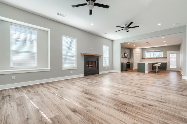 unfurnished living room featuring ceiling fan, light wood-type flooring, and sink