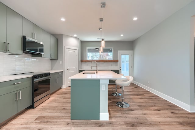 kitchen with sink, stainless steel appliances, tasteful backsplash, light hardwood / wood-style flooring, and decorative light fixtures