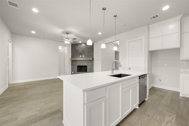 1402 Ethan Cir, Midlothian, TX 76065 - kitchen featuring a sink, ceiling fan, dishwasher, a tiled fireplace, and light wood-type flooring