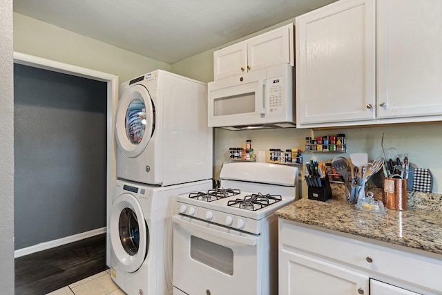 kitchen featuring white cabinetry, light stone counters, white appliances, and stacked washer and dryer