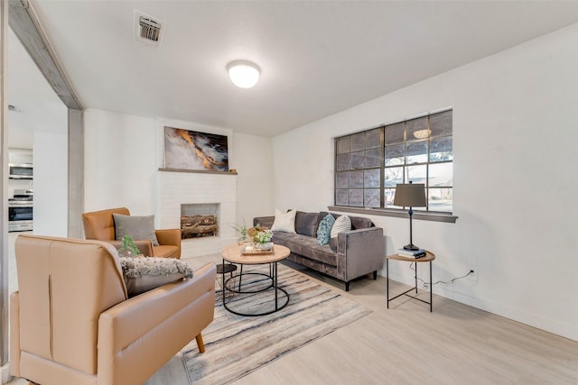 living room featuring wood-type flooring and a brick fireplace