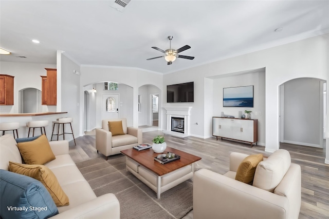 living room with hardwood / wood-style flooring, ornamental molding, and ceiling fan