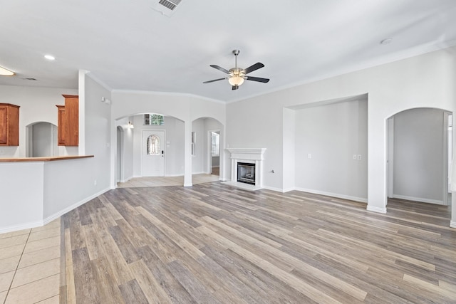 unfurnished living room featuring ceiling fan, ornamental molding, and light hardwood / wood-style floors