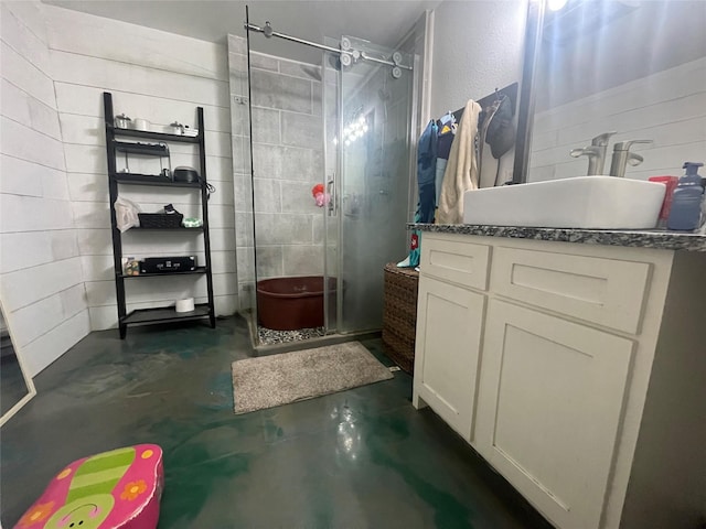 bathroom with concrete flooring, vanity, and a shower with shower door