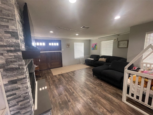 living room with a healthy amount of sunlight, dark wood-type flooring, and ornamental molding