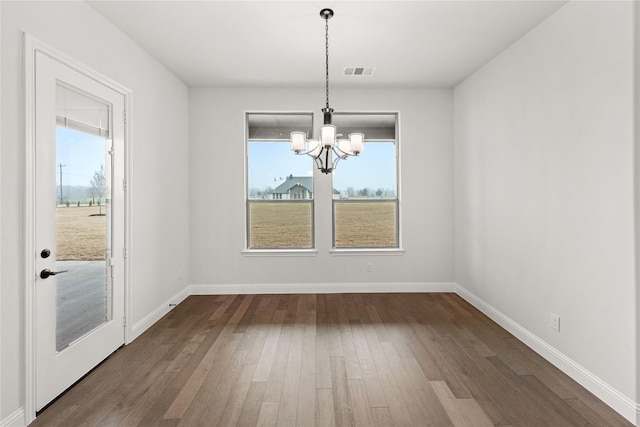 unfurnished dining area with dark wood-type flooring and an inviting chandelier